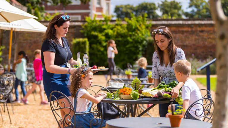 A family sat outside the Orangery Cafe at Ham House during summer